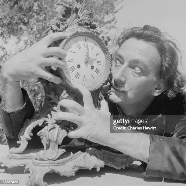 Spanish surrealist artist Salvador Dali clutches an ornate clock at his home in Cadaques on the Costa Brava, Spain, 8th January 1955. Original...