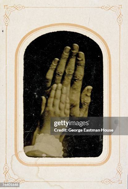 Framed and card mounted tintype closeup of a child's hand atop an adult hand, late 1800s.