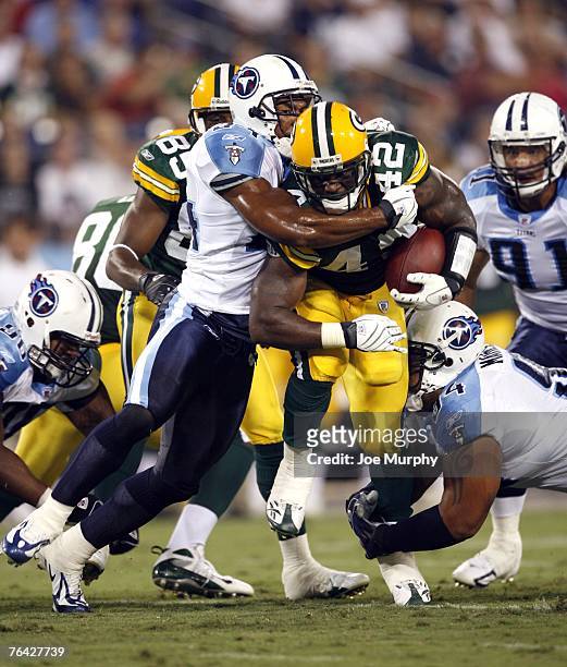 DeShawn Wynn of the Green Bay Packers is tackled by Jesse Mahelona and Chris Hope of the Tennessee Titans during a preseason game on August 30, 2007...