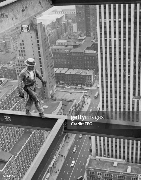 New York construction worker walks along a girder high above the city streets, circa 1950.