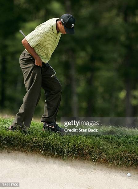 Tiger Woods locates his ball in the bunker at the fourth hole during the first round of the Deutsche Bank Championship at TPC Boston on August 31,...