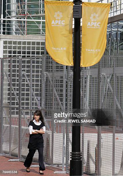 Woman walks past fences and concrete blocks set up as part of security around the Sydney Conventation Centre, 01 September 2007, ahead of the Asia...