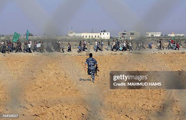 Members of the Hamas Executive Force runs after protestors who are trying to cross the Rafah border in southern Gaza Strip during a protest urging...