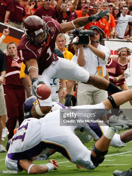 Cornerback Victor "Macho" Harris of the Virginia Tech Hokies leaps over the goal line and quarterback Brett Clay of the East Carolina Pirates for a...