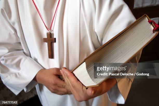 catholic mass. altar boy with holy bible. france. - altar boy stockfoto's en -beelden