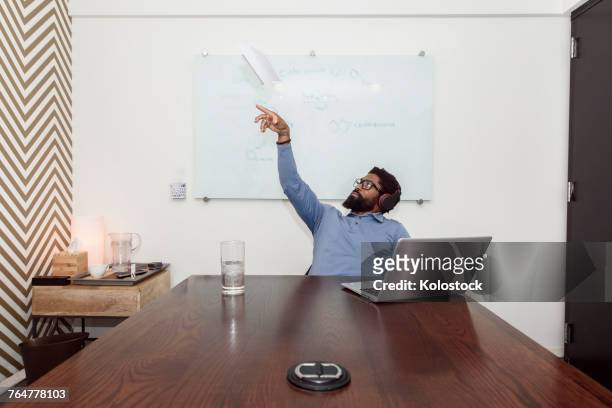 black businessman wearing headphones throwing paper airplane - throwing stock pictures, royalty-free photos & images