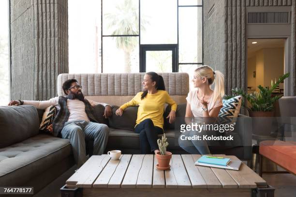 friends talking in lounge - three people on couch stock pictures, royalty-free photos & images