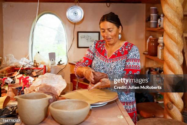 mixed race woman shaping clay in art studio - pueblo villaggio indigeno foto e immagini stock