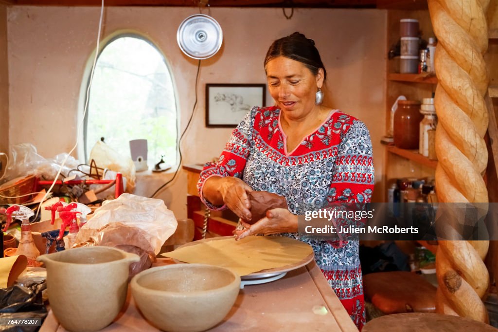 Mixed race woman shaping clay in art studio