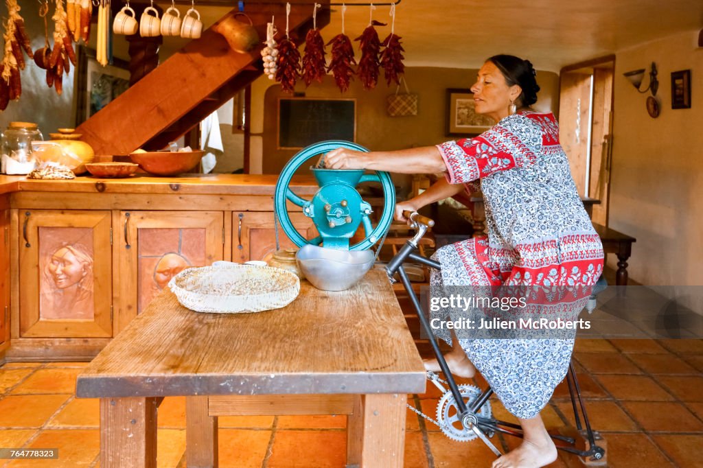Woman pedaling to power grinder in kitchen
