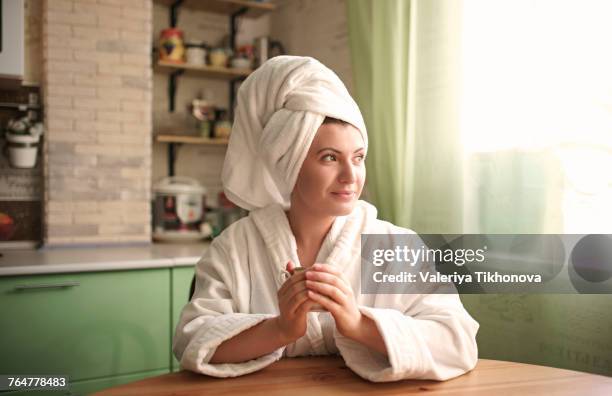 caucasian woman in bathrobe and towel warming hands on cup - envuelto en una toalla fotografías e imágenes de stock