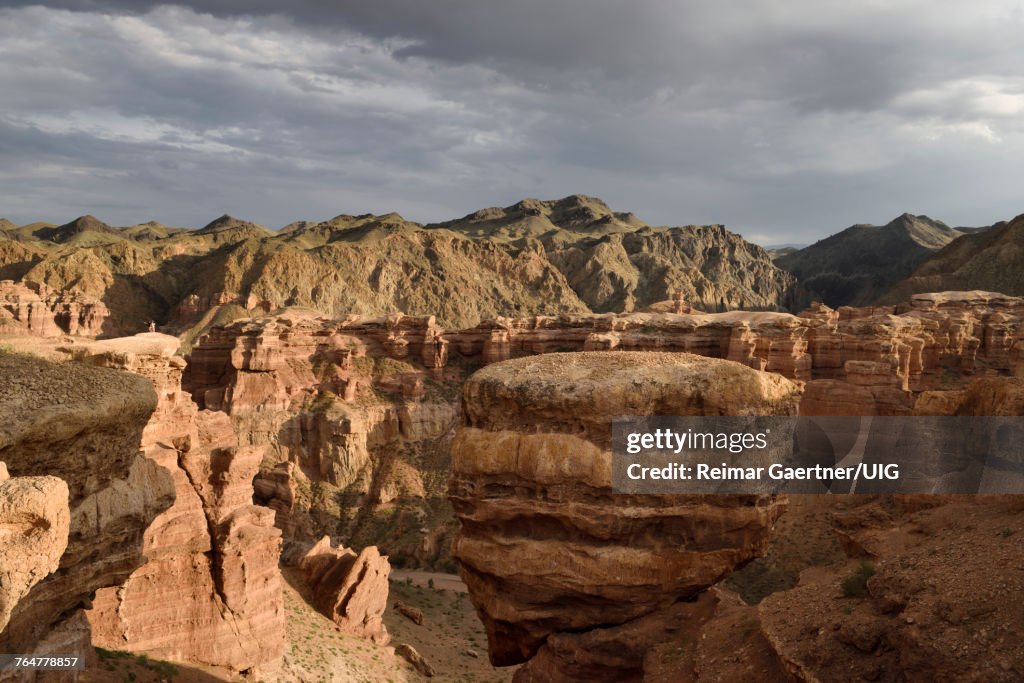 Couple taking selfie at sunset on top of Hoodoo with balancing rock at Charyn Canyon Kazakhstan