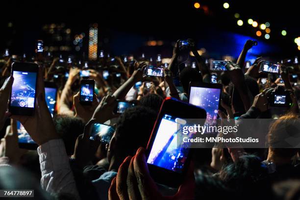 crowd of people recording video with cell phones at night - concierto fotografías e imágenes de stock