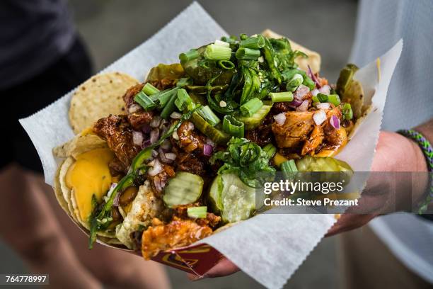 hand holding loaded nachos - nachos stockfoto's en -beelden