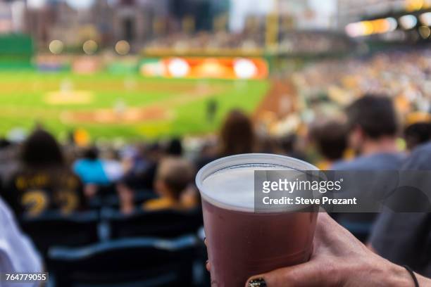 hand of woman holding cup of beer in baseball stadium - avvenimento sportivo foto e immagini stock