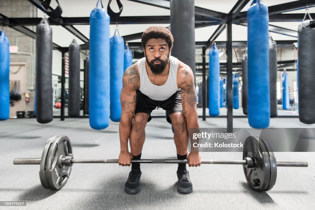 Black man lifting barbell in gymnasium