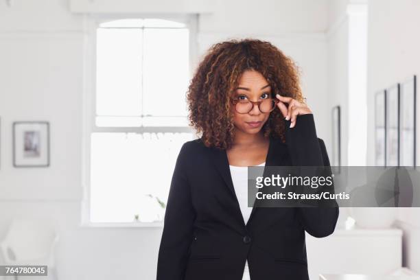 mixed race woman peering over eyeglasses in gallery - suspicion stock pictures, royalty-free photos & images