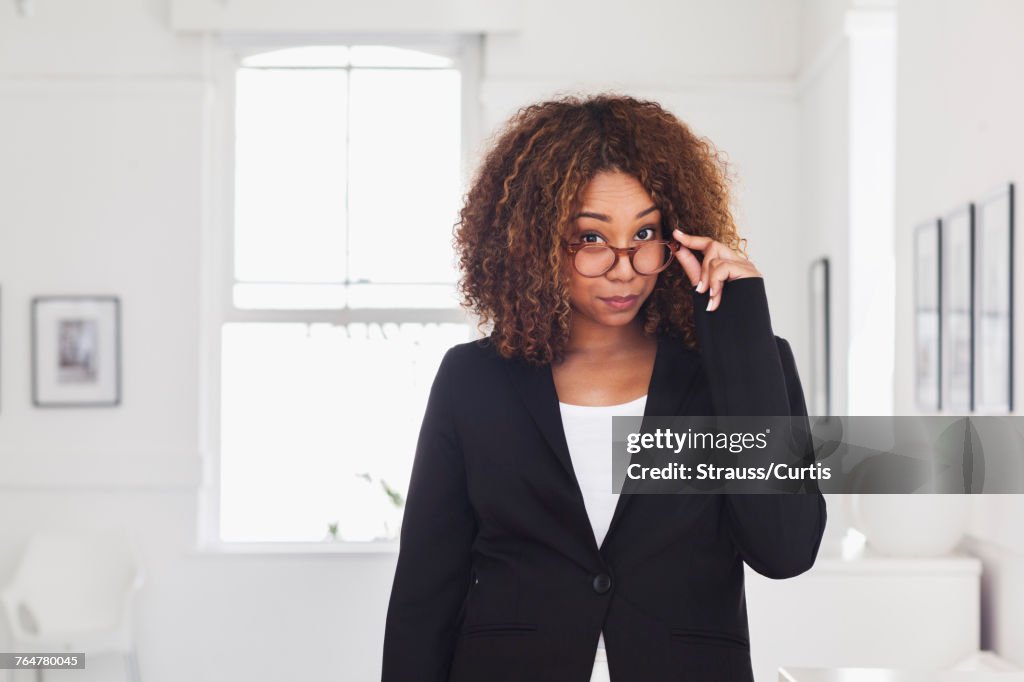 Mixed race woman peering over eyeglasses in gallery