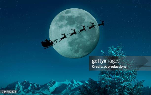 silhouette of santa and reindeer flying sleigh near full moon - santa claus fotografías e imágenes de stock