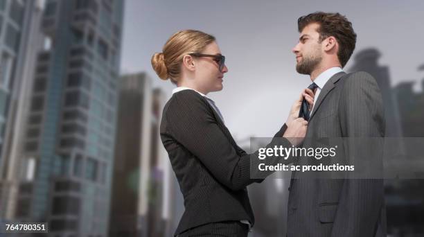 caucasian businesswoman adjusting necktie for businessman - adjusting necktie stockfoto's en -beelden