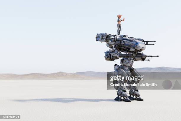 woman standing on futuristic robot aiming guns - transformer stock pictures, royalty-free photos & images