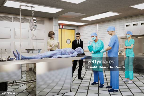 government and doctors examining dead alien - autopsie stock-fotos und bilder