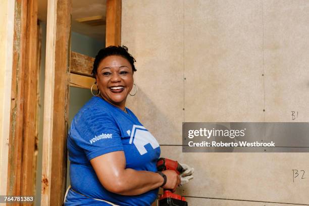 portrait of smiling black woman holding drill - woman volunteer stock pictures, royalty-free photos & images