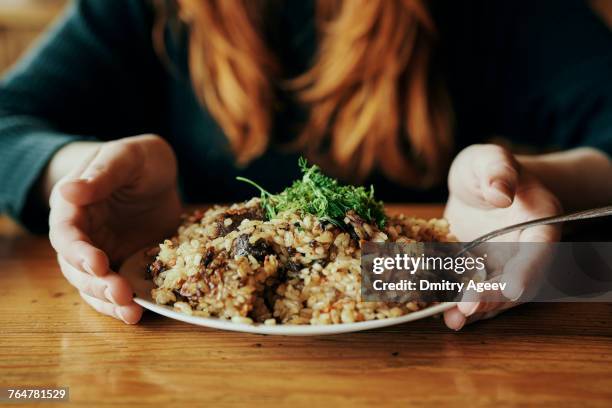 hands of woman holding a plate of rice - entero fotografías e imágenes de stock