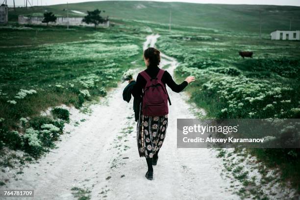 caucasian woman walking on dirt road carrying wildflowers - simferopol stock pictures, royalty-free photos & images