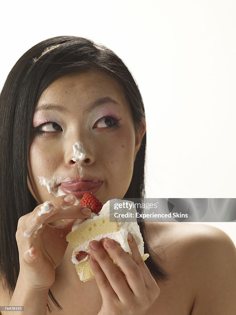 Woman holding a cake with cream on her face