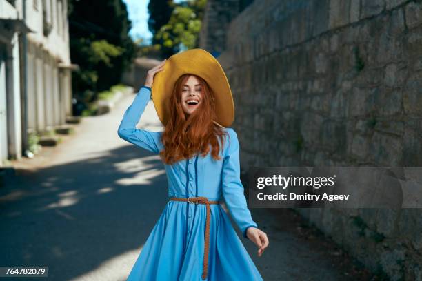 laughing caucasian woman wearing hat near stone wall - stroh stock-fotos und bilder