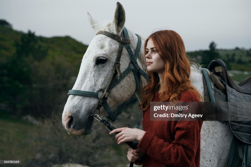 Caucasian woman holding rein of horse