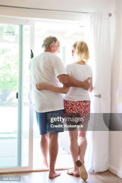 caucasian couple hugging in patio doorway - sliding door exit stock pictures, royalty-free photos & images