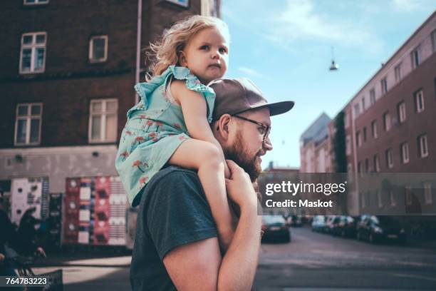 side view of father carrying daughter on shoulders at city street - bära på axlarna bildbanksfoton och bilder