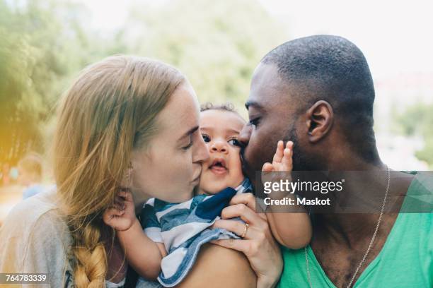 close-up of multi-ethnic parents kissing son - multiracial person stock pictures, royalty-free photos & images