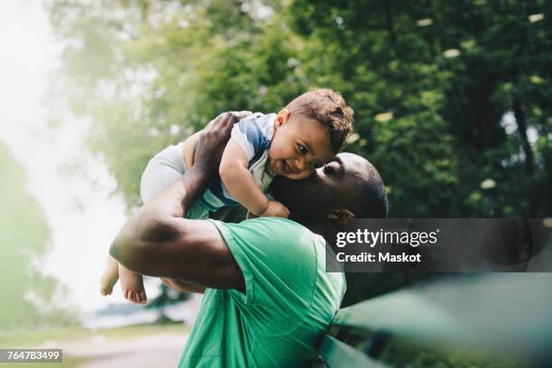 father kissing happy son while carrying at park - baby carrier outside bildbanksfoton och bilder