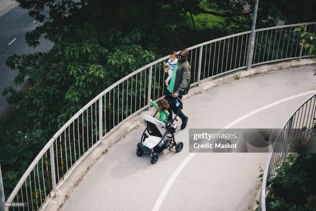High angle view of father with children walking on bridge over trees