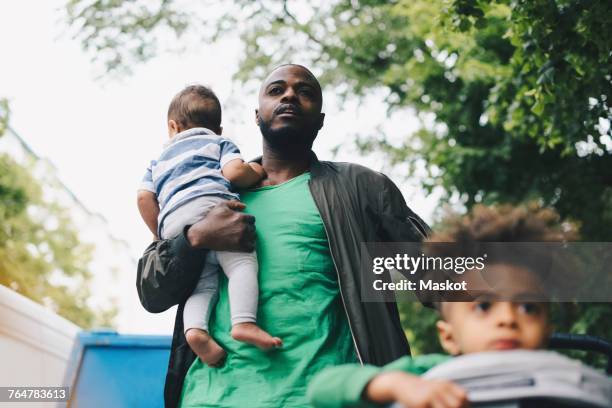 Low angle view of father walking with children in city