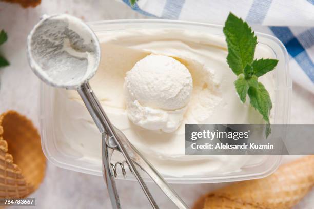 scoop of ice cream in container with mint near cones - vanilleeis stock-fotos und bilder