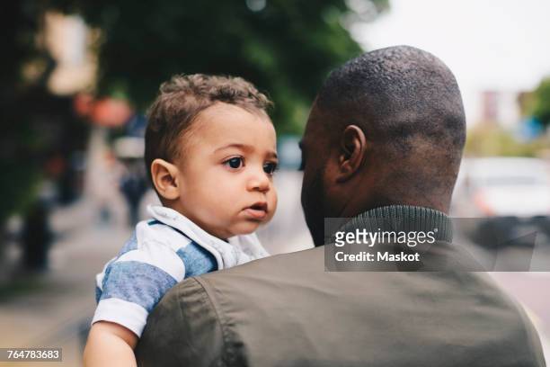 close-up rear view of father carrying toddler - masculinityundonetrend stock-fotos und bilder