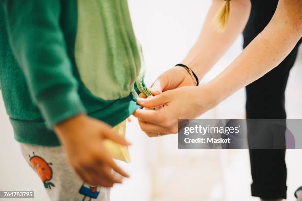 cropped image of mother zipping sons jacket at home - blixtlås bildbanksfoton och bilder