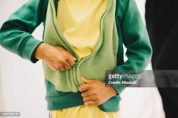 midsection of boy zipping his jacket at home - zipper stock pictures, royalty-free photos & images