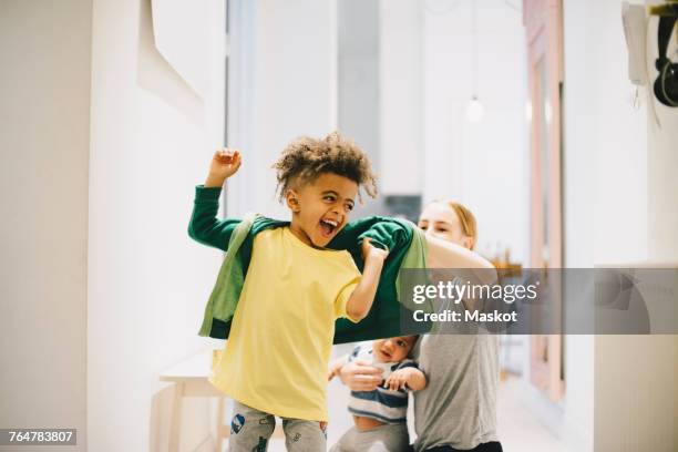 mother with toddler dressing happy son at home - mother and two children feeling good common stockfoto's en -beelden