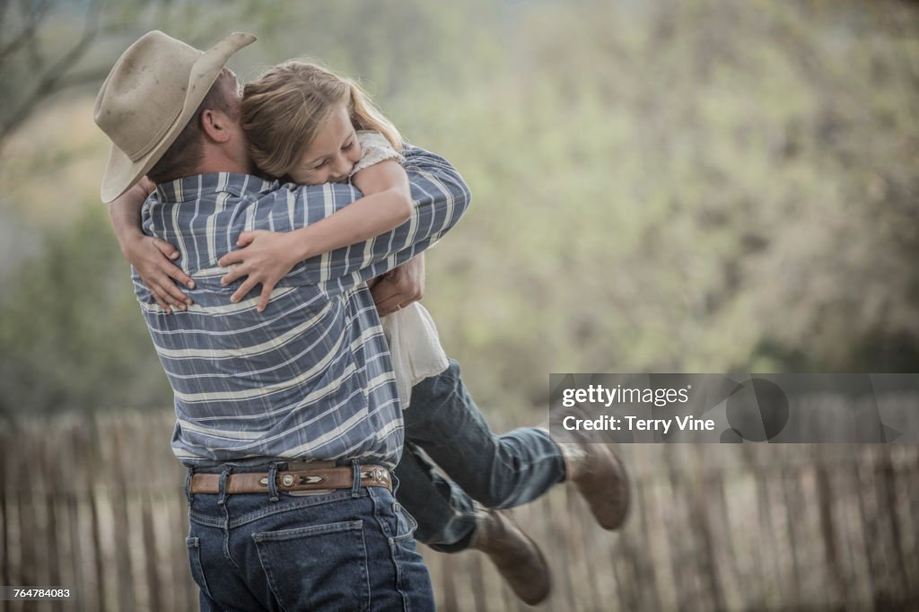 Caucasian father lifting and hugging daughter