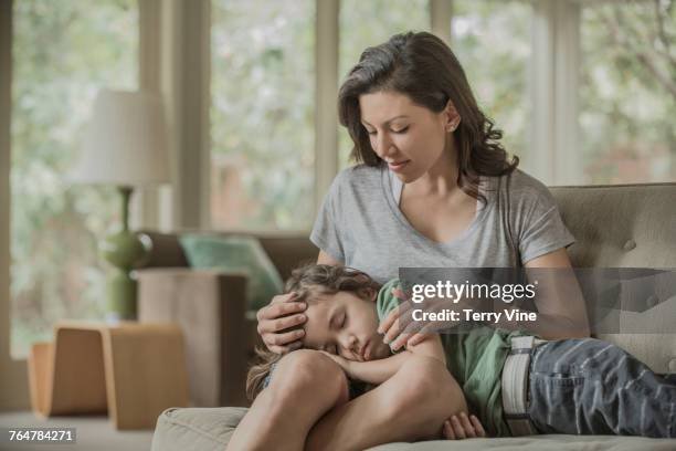 sleeping boy laying in lap of mother - woman home with sick children imagens e fotografias de stock