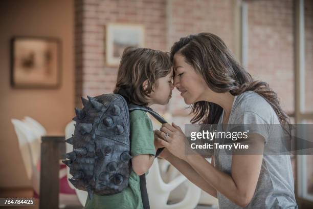 mother rubbing noses with son wearing spiky back - nuzzling stockfoto's en -beelden