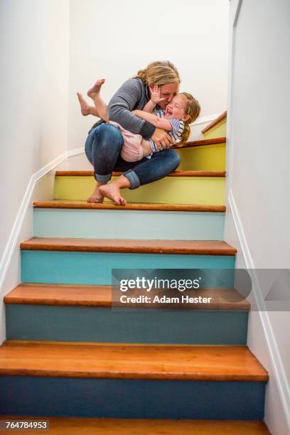 caucasian mother kissing daughter on staircase - family tree stockfoto's en -beelden