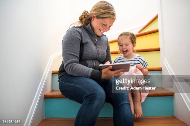 caucasian mother and daughter using digital tablet on staircase - mother happy reading tablet stock pictures, royalty-free photos & images