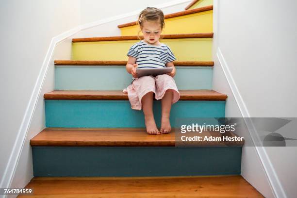 caucasian girl using digital tablet on staircase - child sitting stock-fotos und bilder