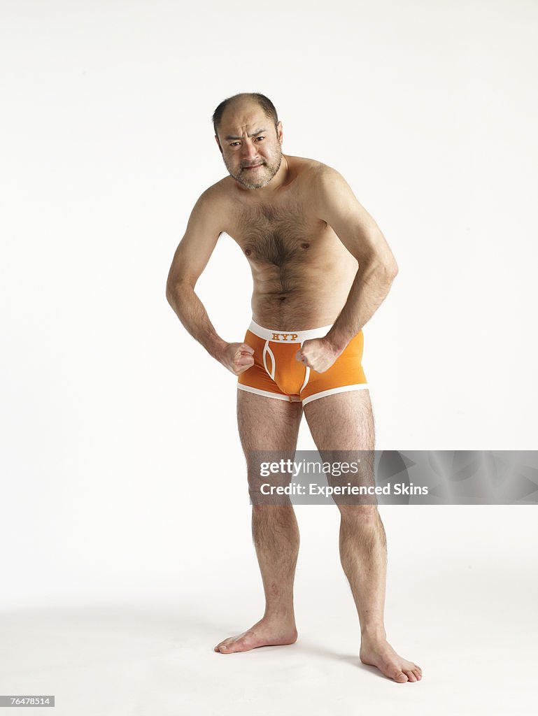 Mature man in orange briefs, flexing his muscles